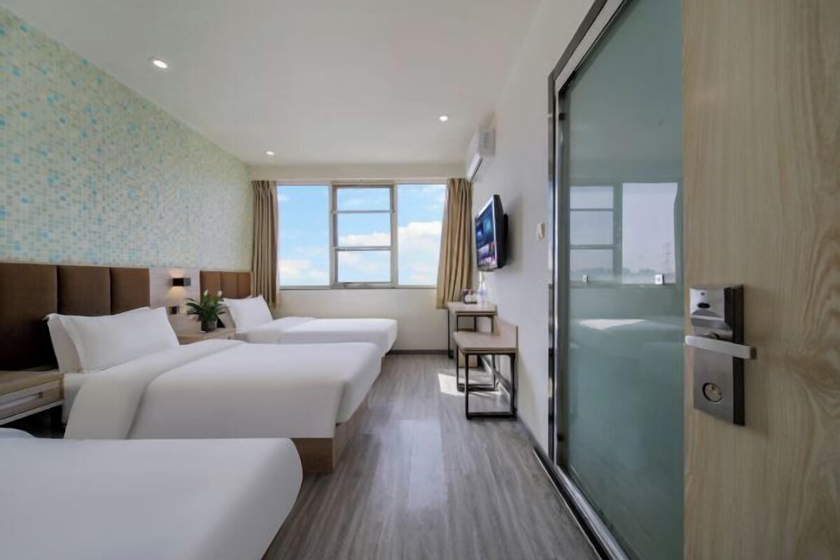 A hotel room with two beds, a TV, a window with a view, and a sliding door.