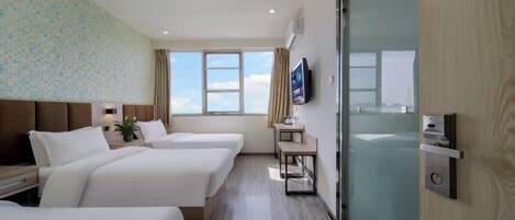 A hotel room with two beds, a TV, a window with a view, and a sliding door.