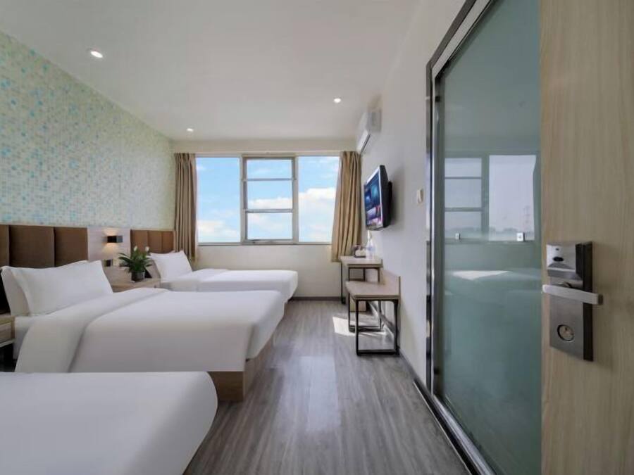 Quarto de hotel com duas camas, televisão, janela com vista e porta deslizante.
