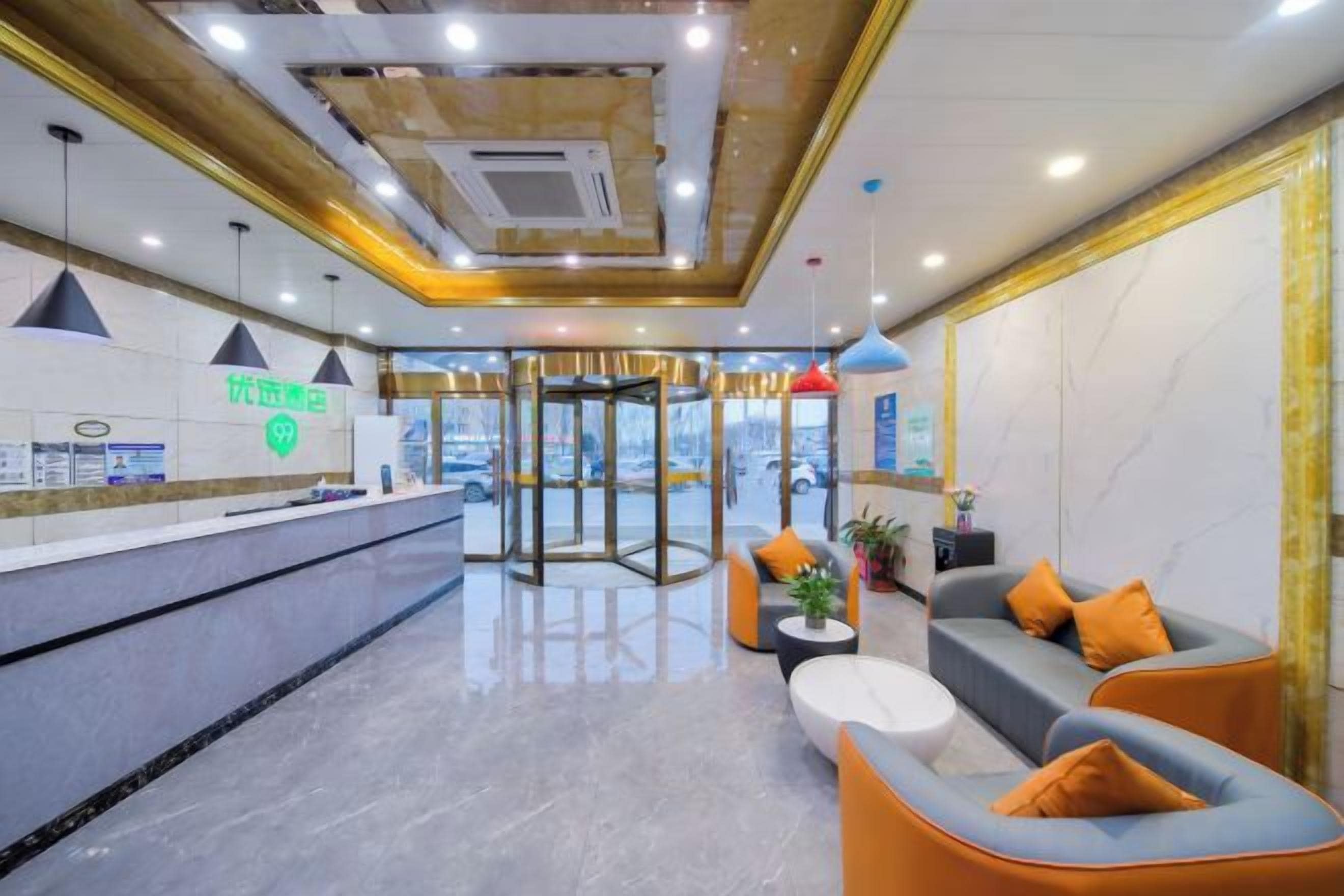 A hotel lobby with a reception desk, seating area, and a revolving door.