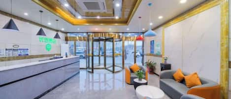 A hotel lobby with a reception desk, seating area, and a revolving door.