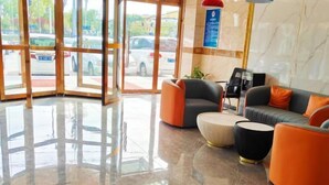 A lobby with a marble floor, seating area with orange and grey sofas, and a glass door leading outside. - 99inn Selected (Beijing Huilongguan East Street Metro Station) (Beijing)