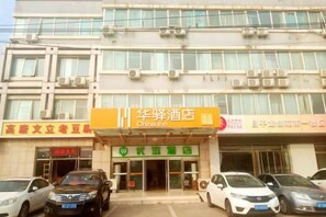 Un hotel con un cartel llamativo que dice China Inn, varios coches aparcados y una fachada de edificio con unidades de aire acondicionado.
