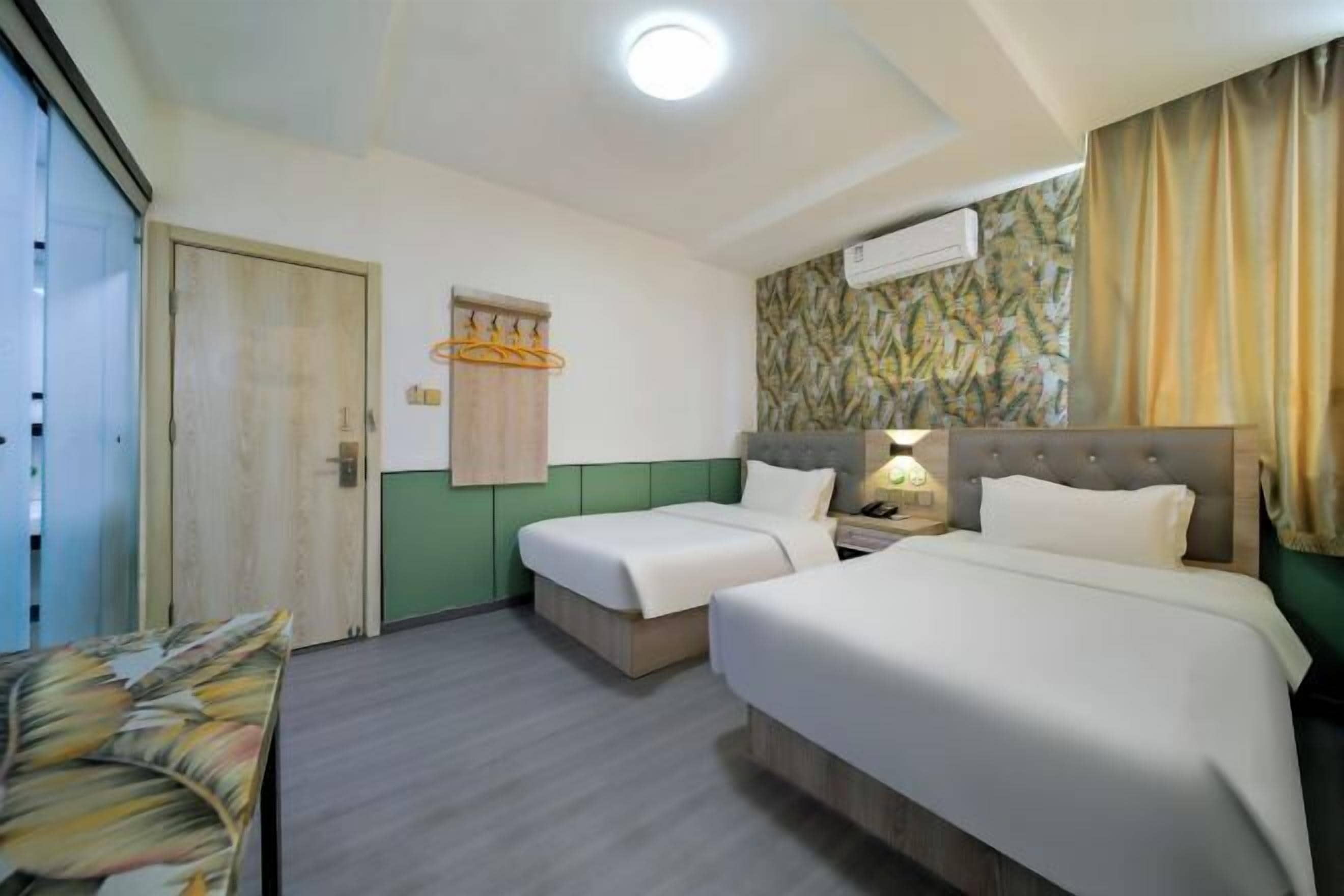 A hotel room with two beds, a desk, a chair, and a hanging light fixture.