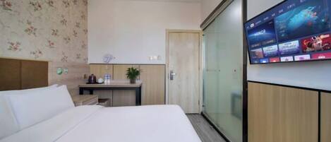 Ein Hotelzimmer mit einem Bett, einem Schreibtisch, einem an der Wand montierten Fernseher und einer Schiebetür.
