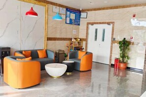 Un hall de hotel con arreglos de asientos, una recepción y una planta.