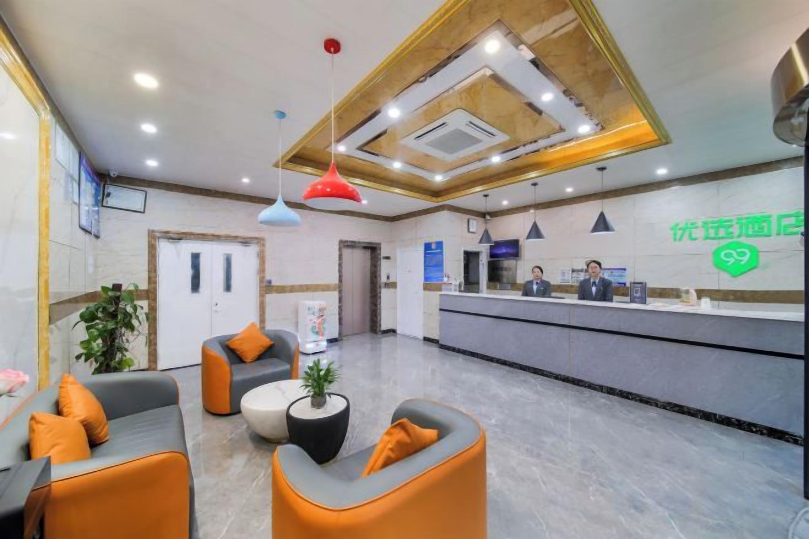 Un hall de hotel con mostrador de recepción, zona de estar y una planta.