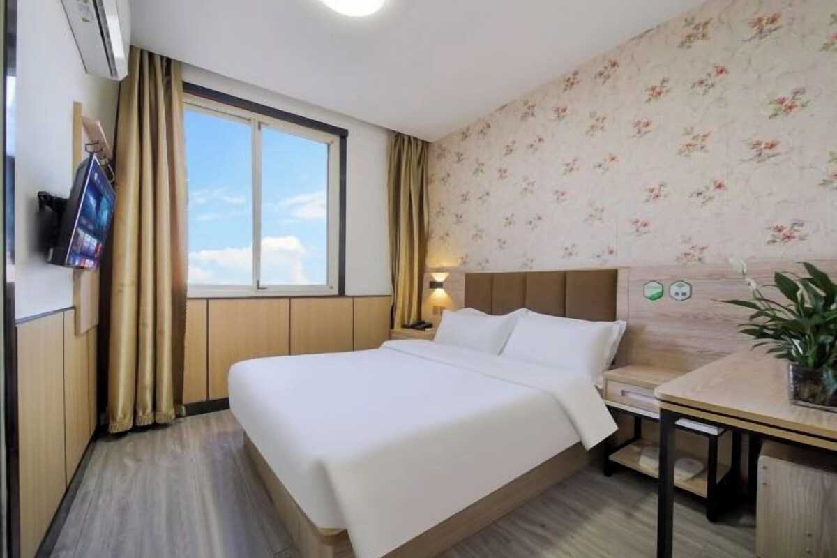 Une chambre d’hôtel avec un lit, un bureau, une télévision et une fenêtre avec des rideaux.