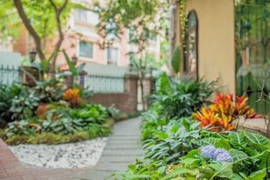A pathway leading through a garden with various plants and a building in the background. - The Brilliant House (Chengdu)