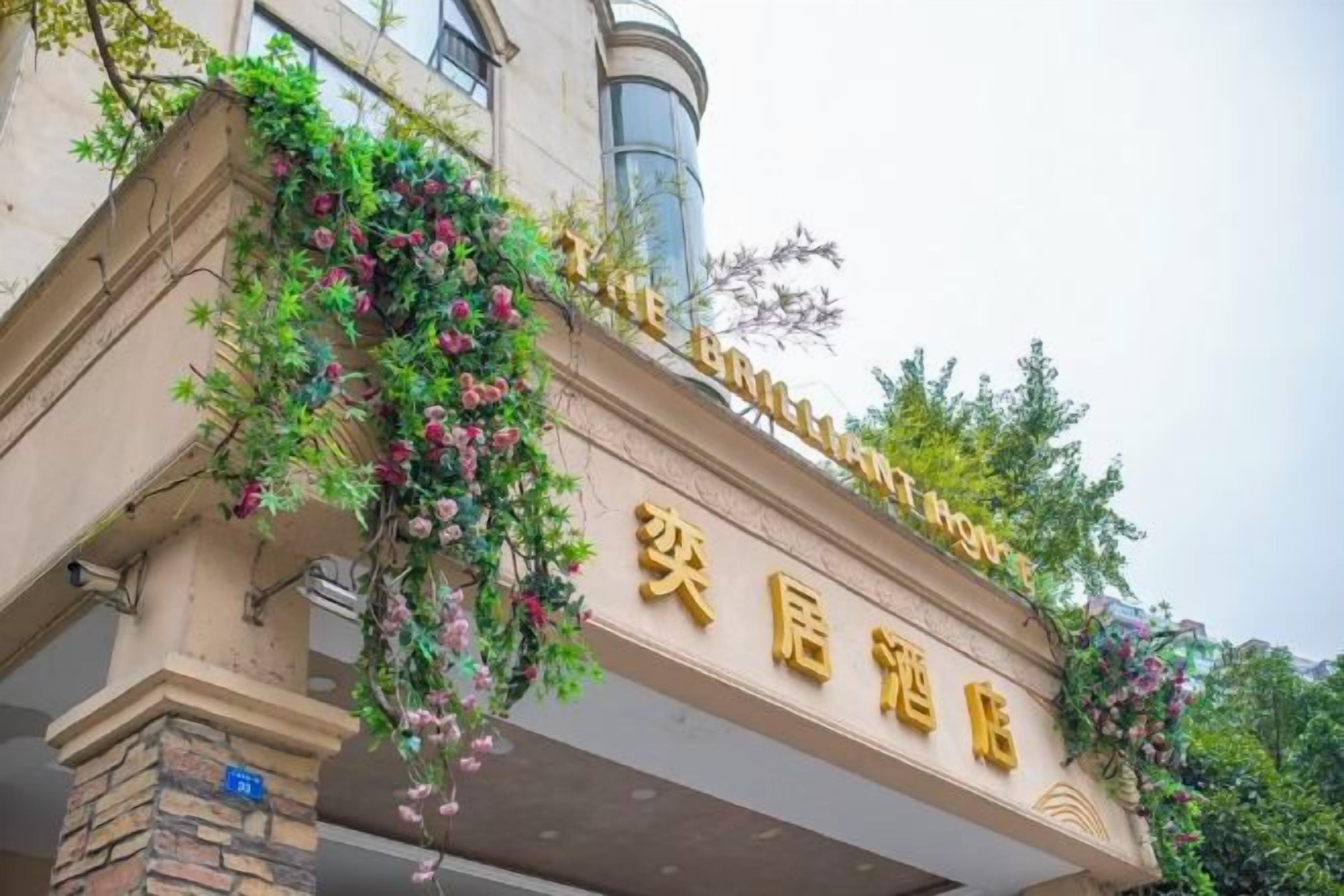 Entrada de um hotel com uma placa que diz "The Brilliant Hotel" e "The Brilliant Hotel" em caracteres chineses.