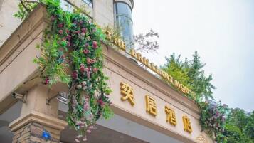 Entrada de um hotel com uma placa que diz "The Brilliant Hotel" e "The Brilliant Hotel" em caracteres chineses.
