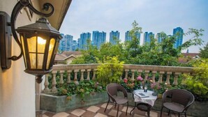 A balcony with a checkered floor, two wicker chairs, a table with a white tablecloth, and a lit lantern. - The Brilliant House (Chengdu)