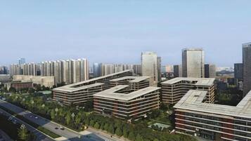 A high-rise building complex with multiple floors, surrounded by greenery and a clear sky.