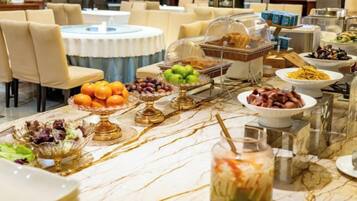 A buffet table with various food items and a glass of juice.