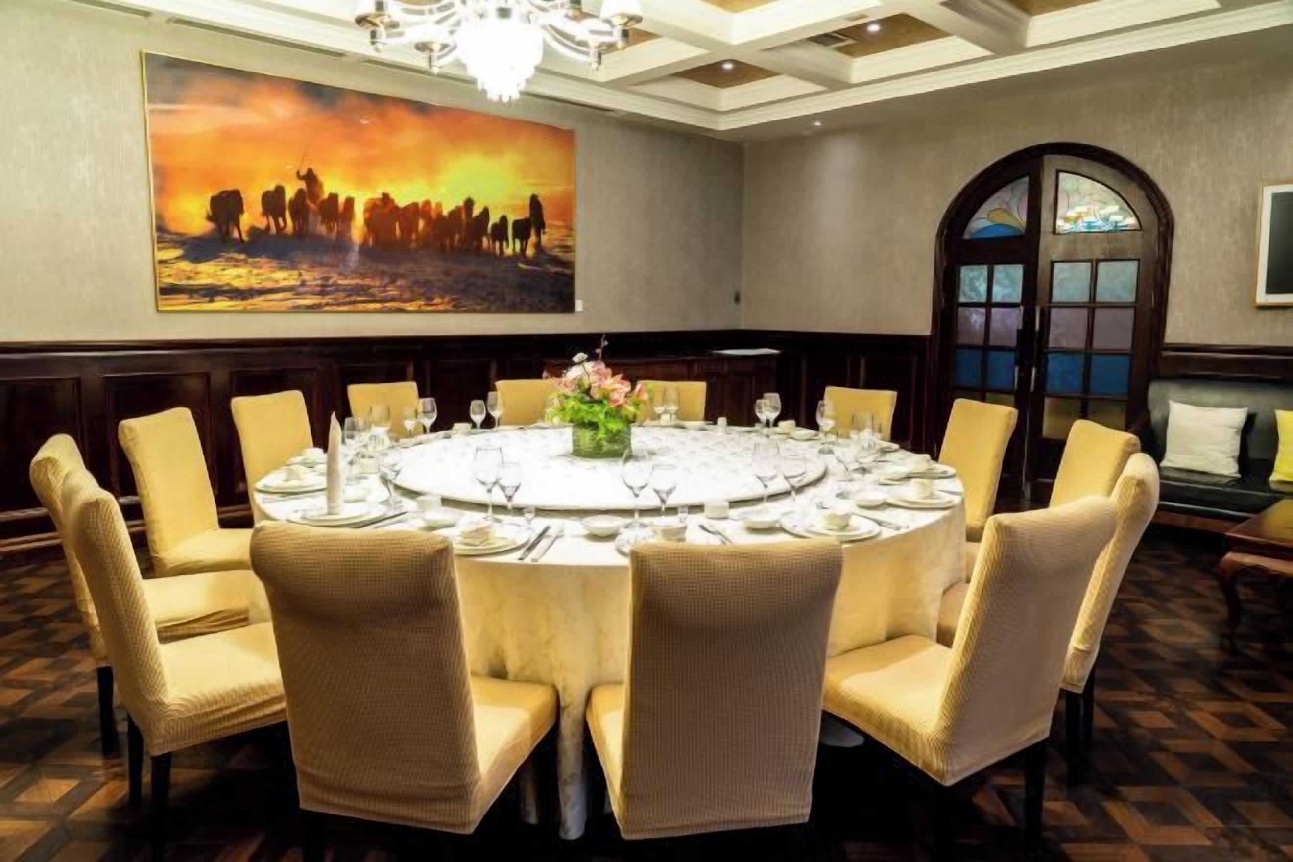 A conference room with a round table, chairs, and a large painting on the wall.