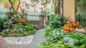 A pathway flanked by lush greenery and a brick wall. - The Brilliant House (Chengdu)