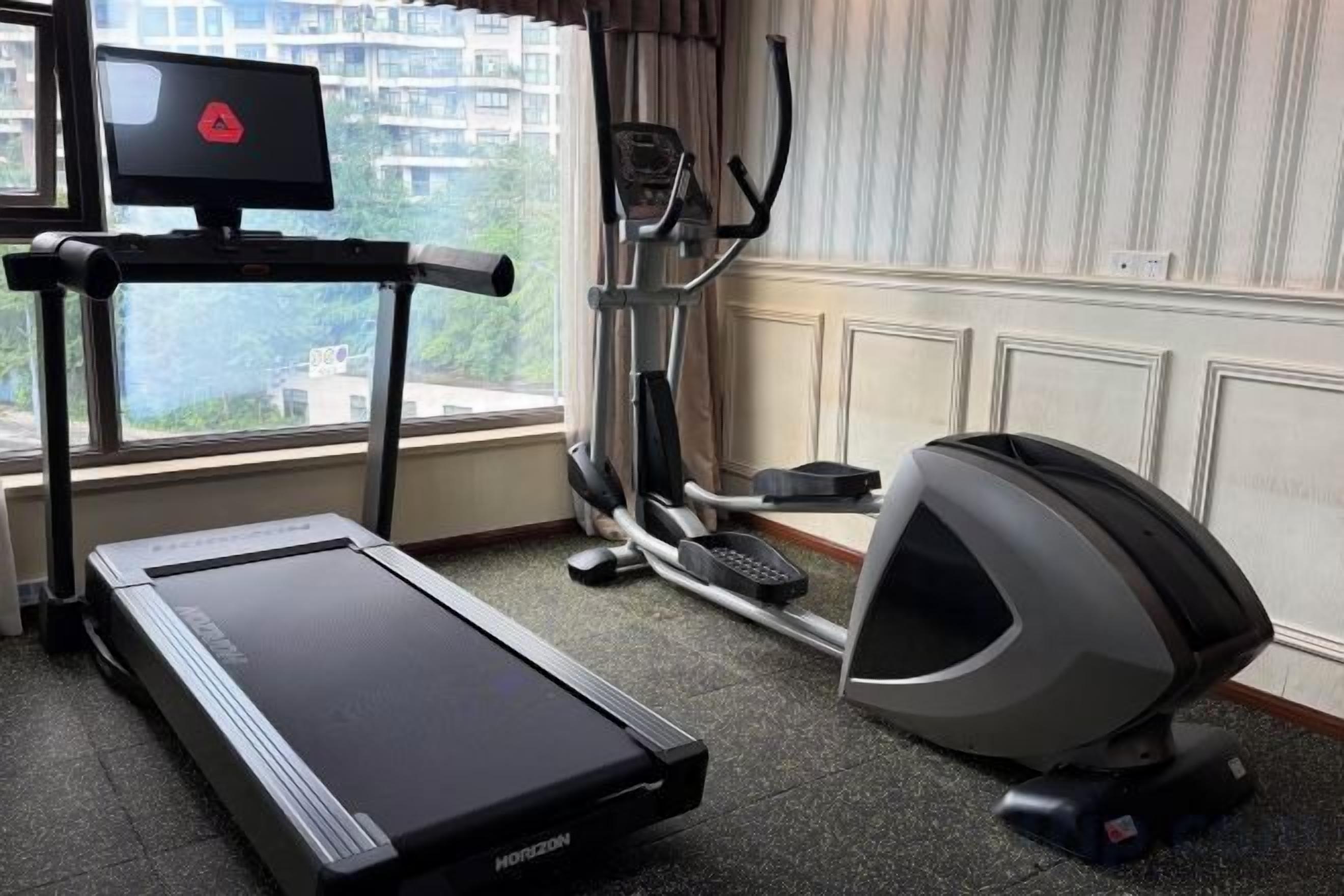 A home gym with a treadmill, elliptical, and stationary bike.