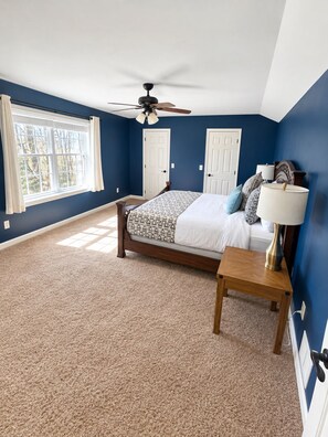 A bedroom with a bed, a nightstand, a ceiling fan, and a window with curtains. - Tranquil Farmhouse Retreat (Montville)