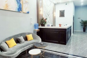 Un hall d’entrée moderne avec un canapé, une petite table ronde, un comptoir d’accueil et une plante en pot.