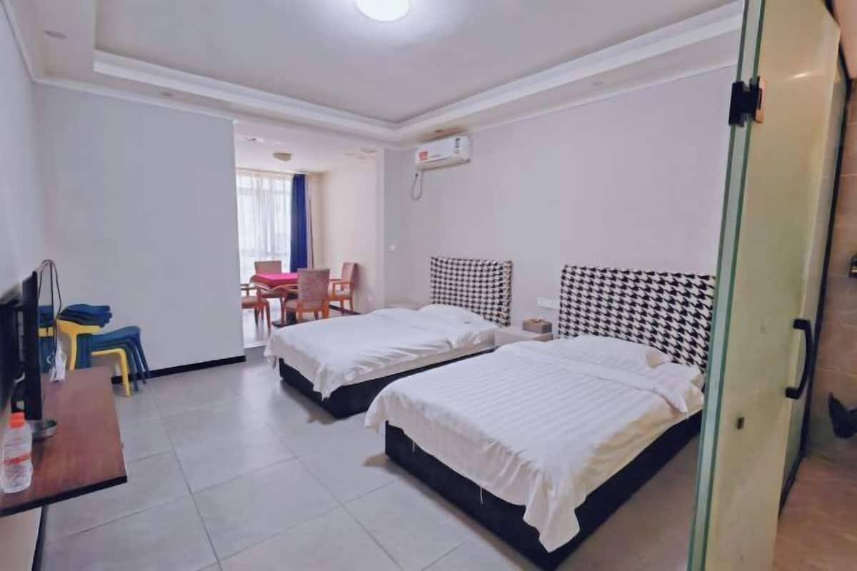 A hotel room with two beds, a desk, a chair, and a small table.