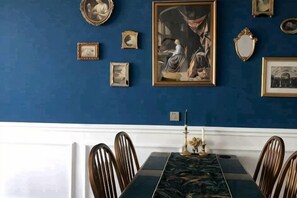 Une salle à manger avec une table, des chaises et des œuvres d’art encadrées accrochées au mur.