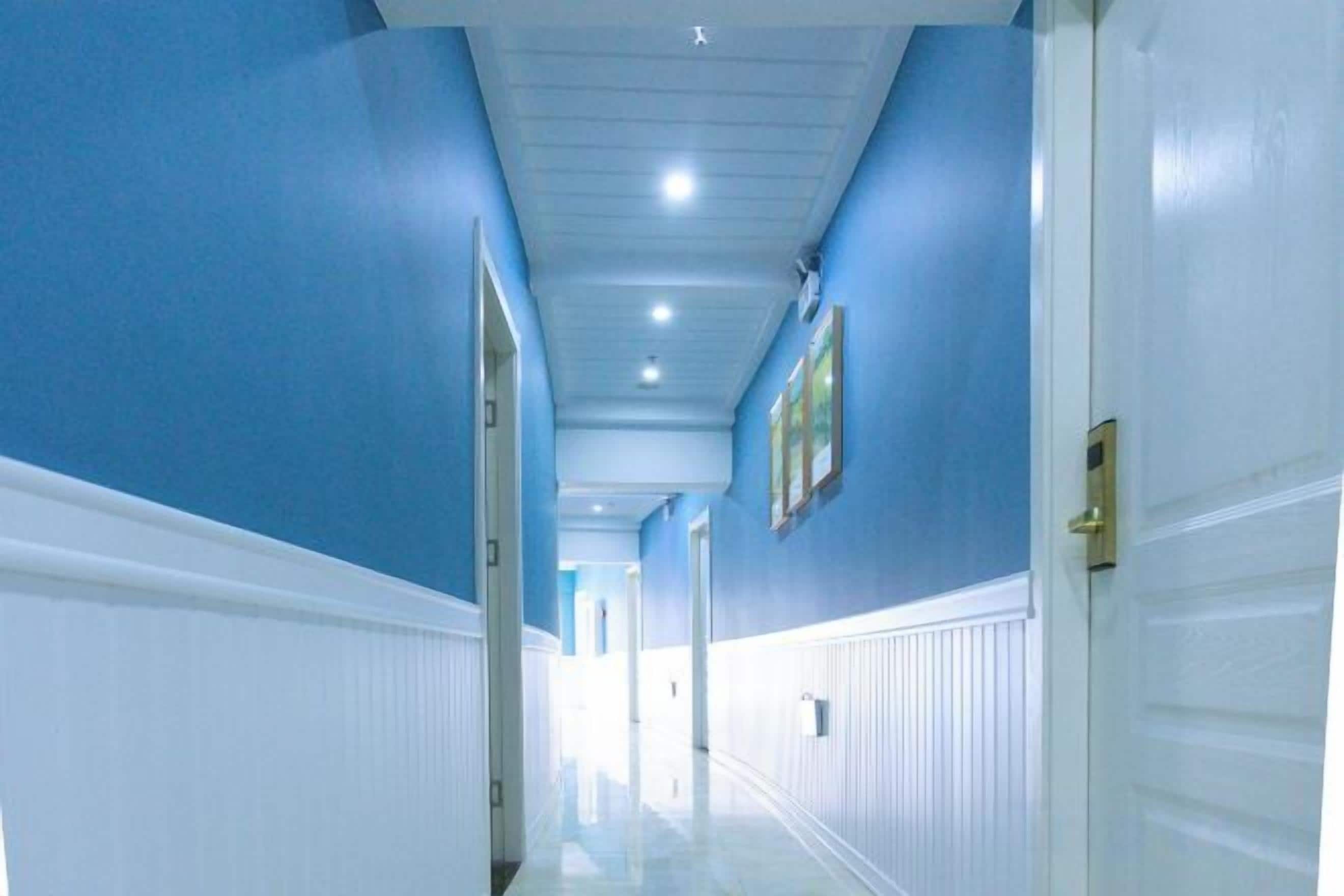 A hallway with white wainscoting, blue walls, and a door on the right.