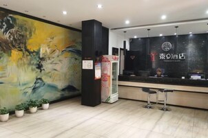 Zona de recepción de hotel con un cuadro abstracto grande, un mostrador de recepción y un mostrador con un logotipo.