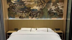 A hotel room with a bed, nightstands, and a large wall mural. - Tai 9 Hotel (duelbert) (Dorbod County)