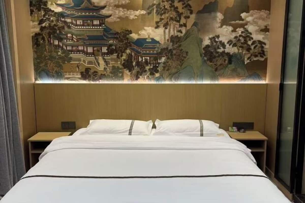 A hotel room with a bed, nightstands, and a large wall mural.