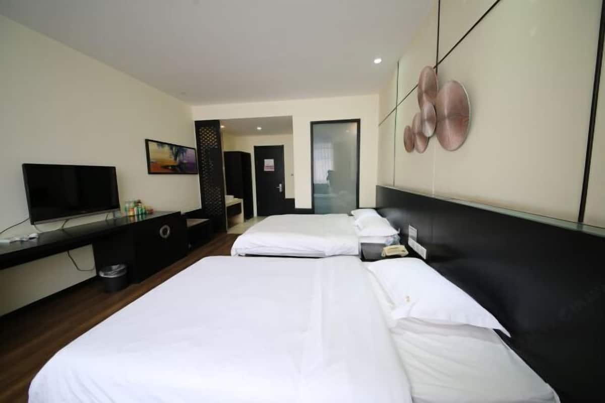 A hotel room with two beds, a TV, a desk, and a bathroom door.
