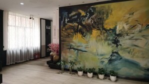 A spacious lobby with a large abstract painting on the wall, potted plants, and a large window with sheer curtains. - Tai 9 Hotel (duelbert) (Dorbod County)