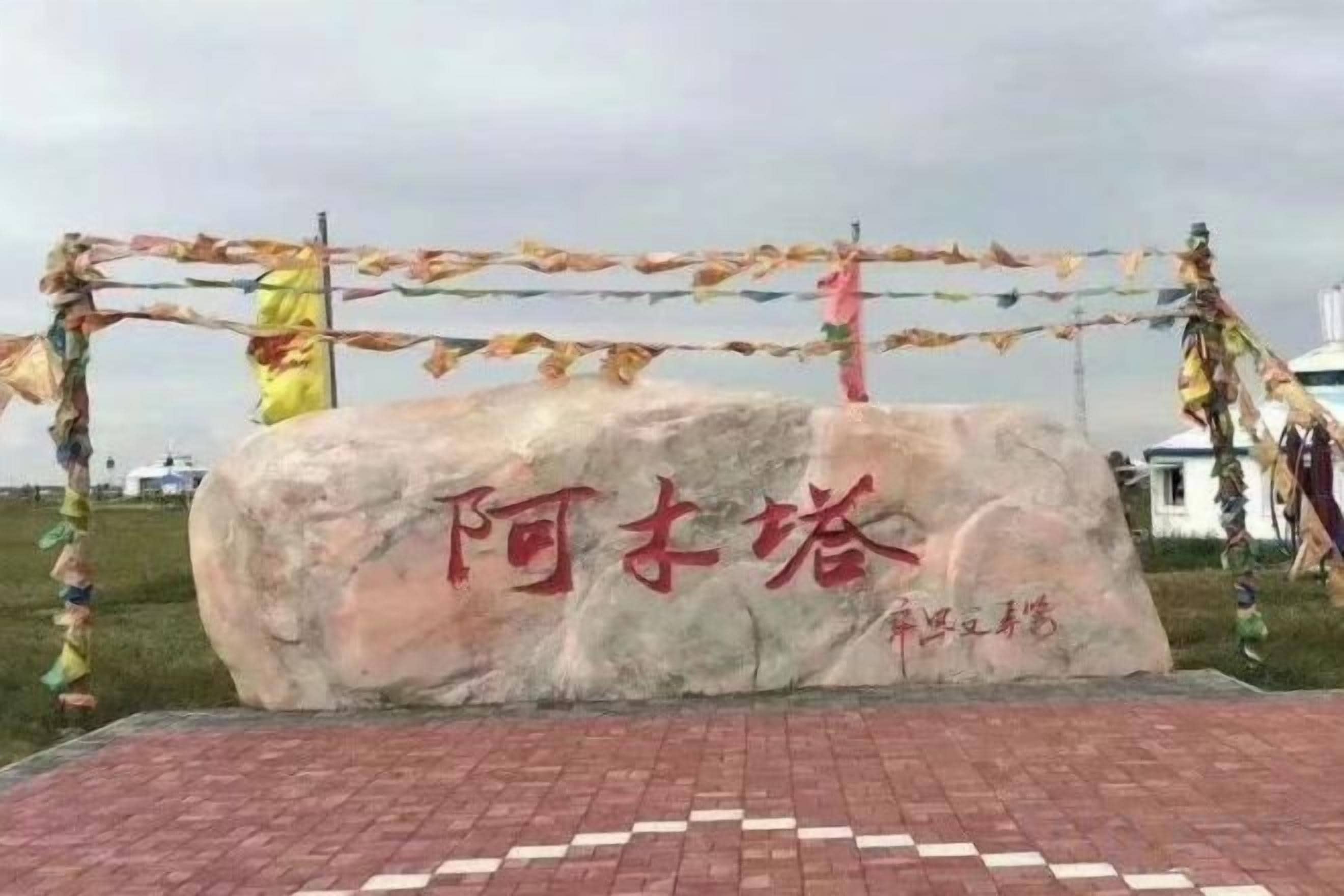 Una gran roca con inscripciones, rodeada por una barrera de cuerda y banderas de colores.