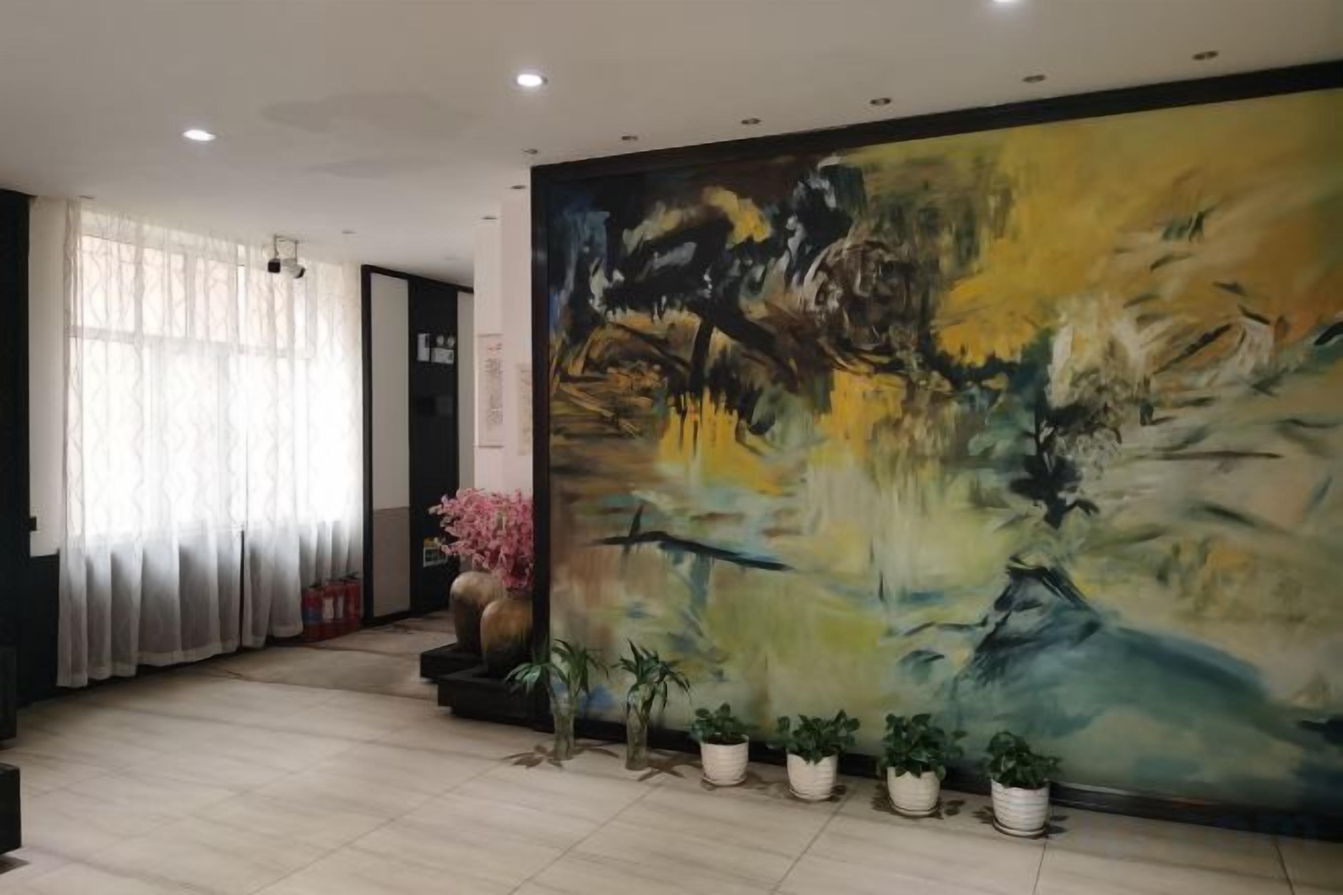 A hotel lobby with a large abstract painting, potted plants, and a tiled floor.