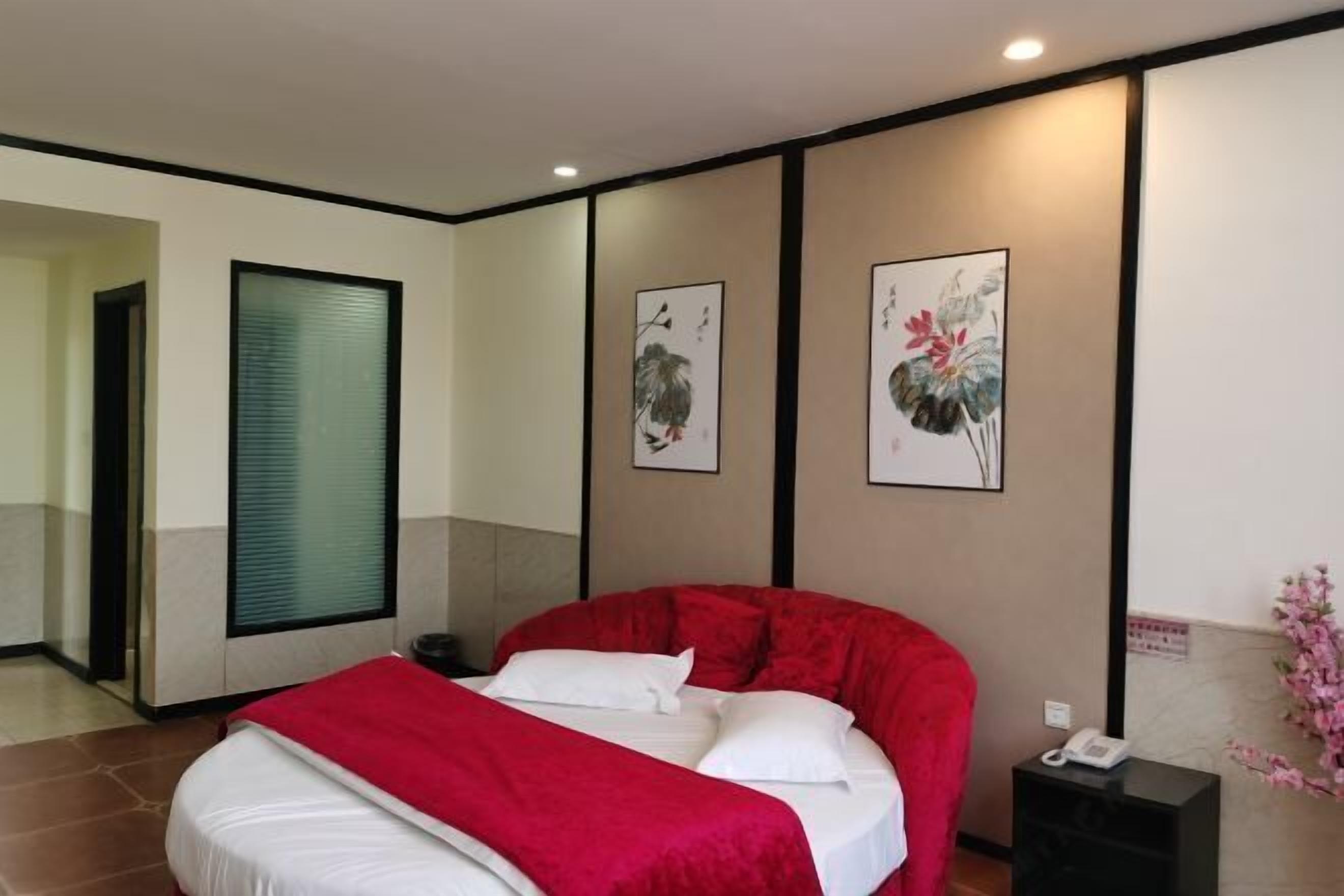 A hotel room with a large bed, a bedside telephone, and artwork on the walls.