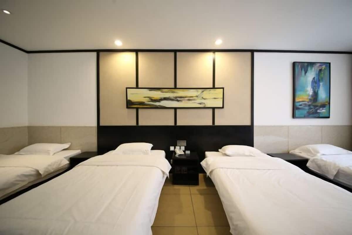 A hotel room with two single beds, a nightstand, and a painting on the wall.