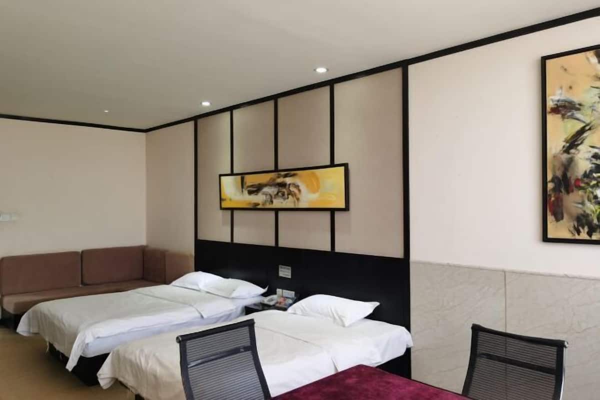 A hotel room with two beds, a sofa, a dining table, and a painting on the wall.