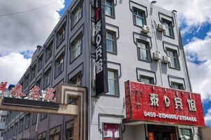 Un edificio de varios pisos, con un llamativo letrero rojo con texto blanco y un número de teléfono.