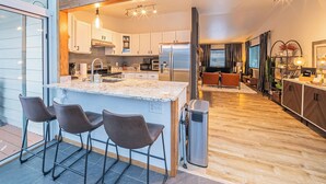 A modern kitchen with a large island, bar stools, and a skylight.