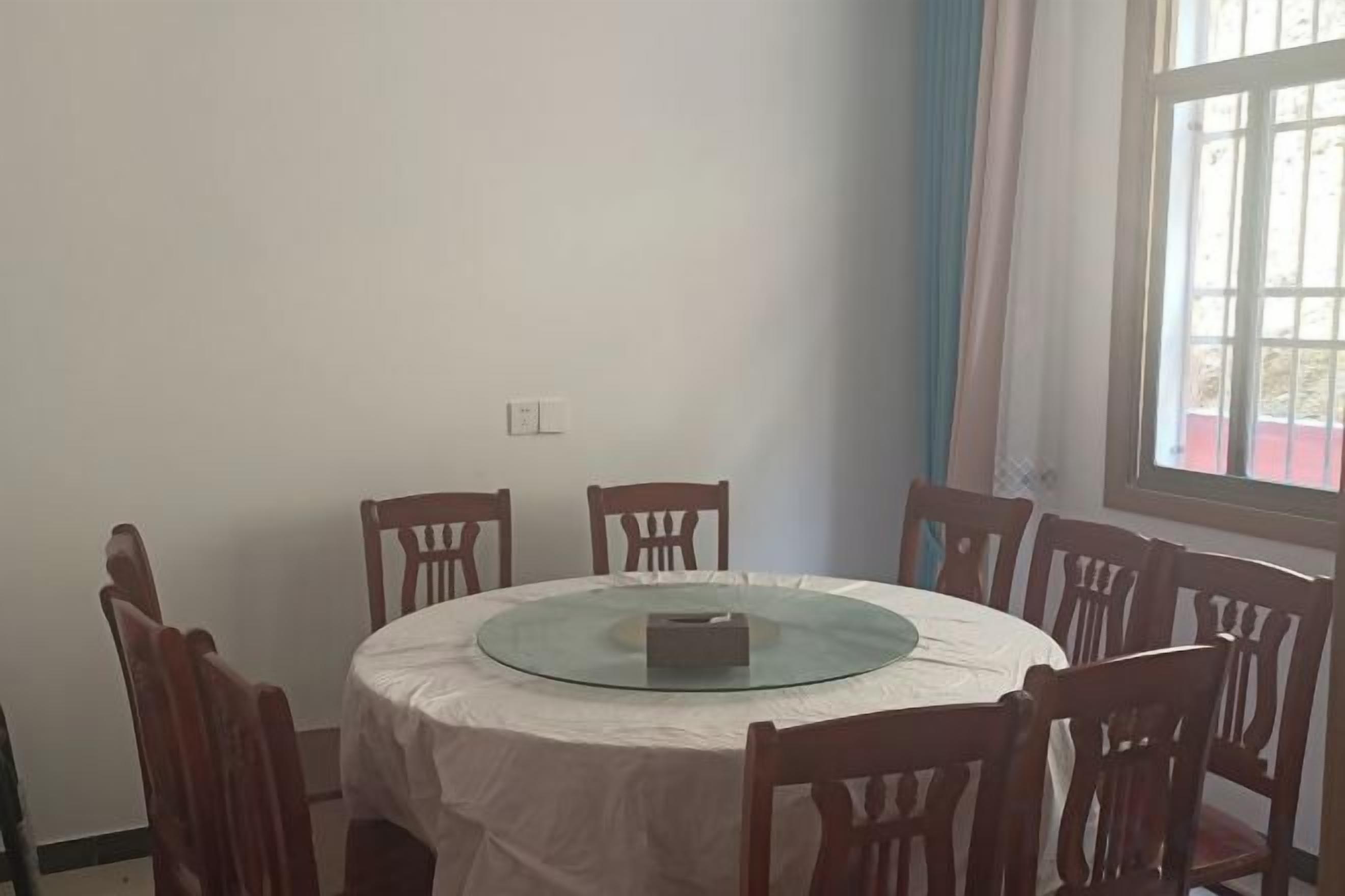 Una mesa de comedor redonda con cubierta de vidrio, rodeada de sillas de madera.