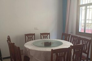 A round dining table with a glass top, surrounded by wooden chairs.