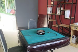A billiards table with a green felt surface and a red felt cushion, surrounded by a red wall with a black metal shelf unit.