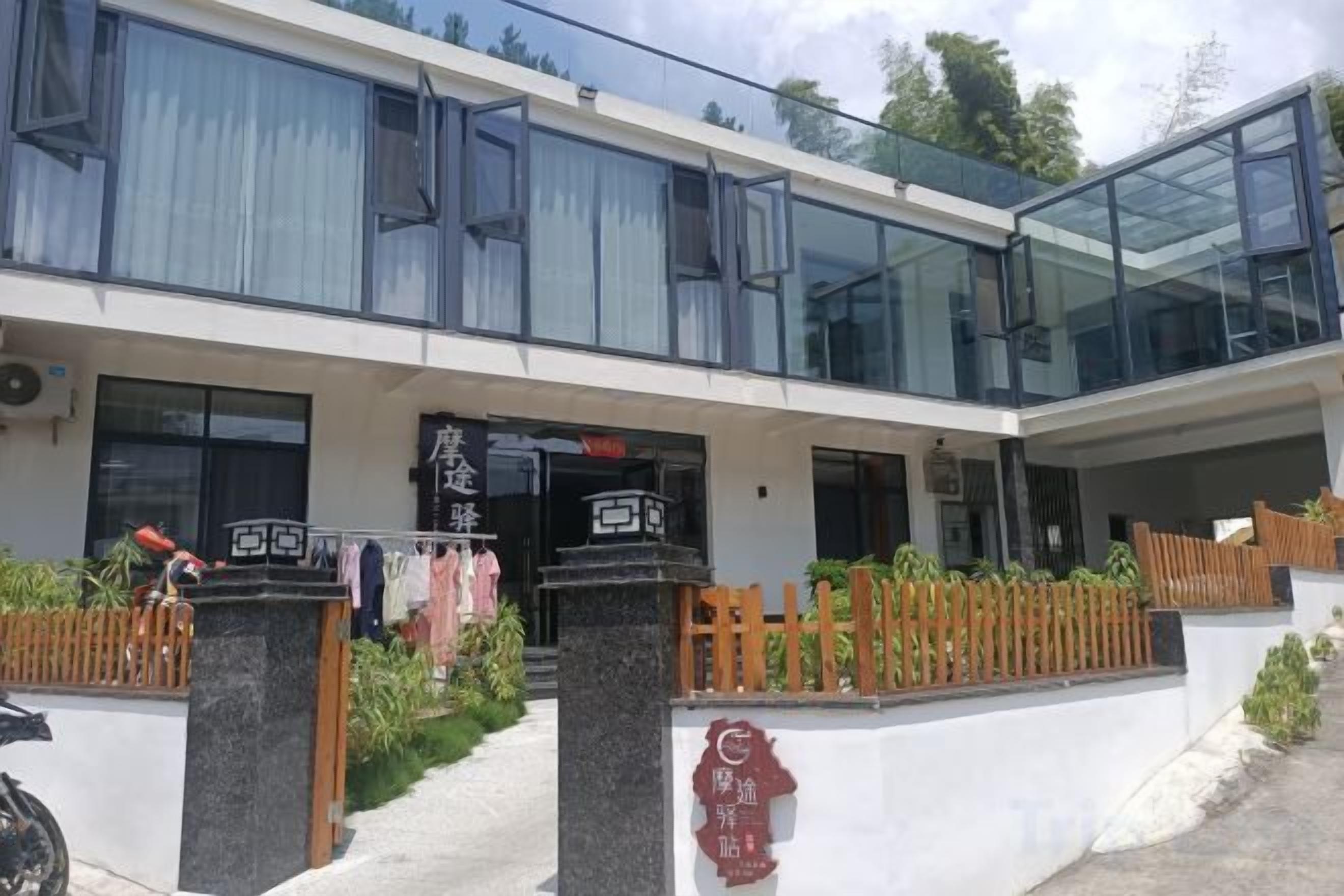 A modern building with a glass facade, a visible entrance, and a signboard.