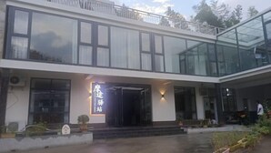 A modern building with a glass entrance, a sign reading "Mansion Drive Station," and a balcony with railings.