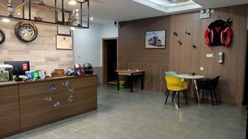 A reception area with a wooden desk, a yellow chair, and a wall-mounted motorcycle helmet.