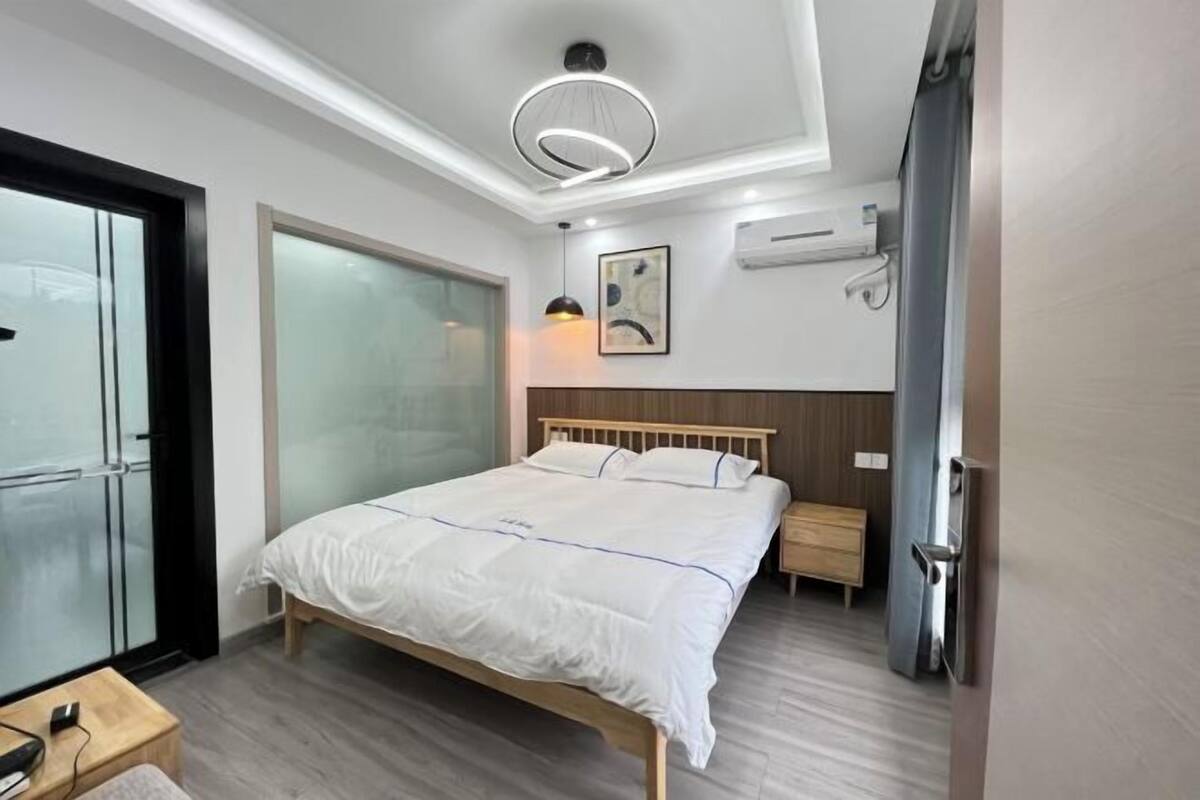 Een moderne slaapkamer met een houten bed, een nachtkastje, een wandairconditioner en een plafondlamp.