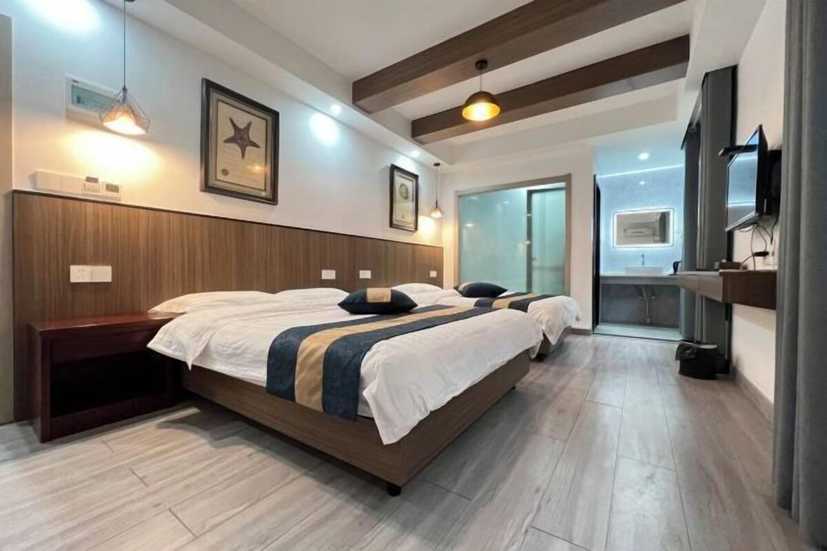 Een moderne slaapkamer met een groot bed, houten hoofdbord, hanglampen en een televisie.