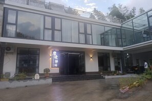 Een modern gebouw met een glazen gevel, een opvallende ingang en een balkon met een hekwerk.