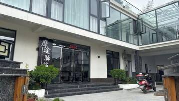 A modern building with a glass facade, a black entrance door, and a sign with Chinese characters.