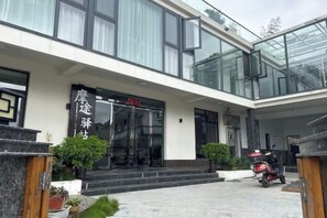 Un edificio moderno con fachada de vidrio, puerta de entrada negra y un letrero con caracteres chinos.