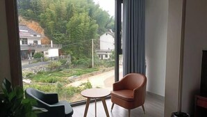 A room with a large window, a small round table, two chairs, and a potted plant.